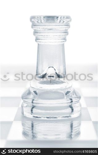 glass chess rook is standing on board, cut out from white background