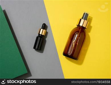 glass cosmetic brown bottles with a pipette on a yellow background. Cosmetics SPA branding mockup, top view