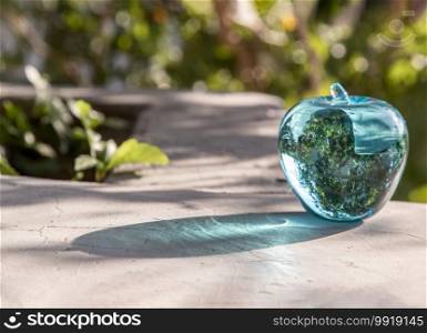 Glass/Crystal blue apple and reflective surface on a natural green background. Copy space, Selective focus.