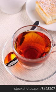 Glass cup of black tea on napkin with cake