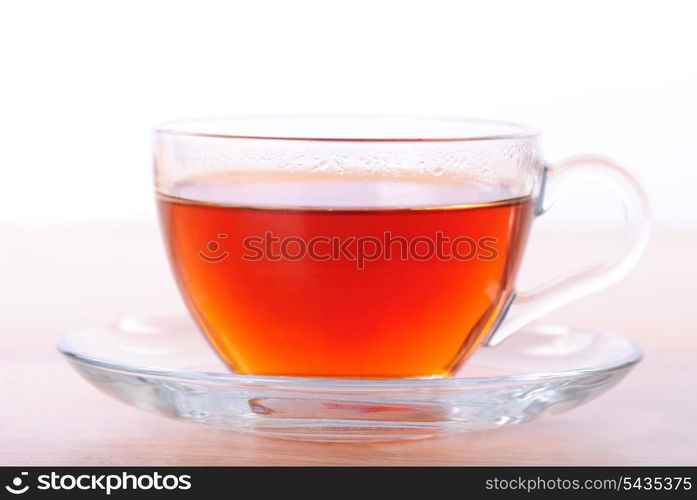 Glass cup of black tea on wooden table