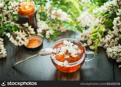 Glass cup of herbal acacia tea with spoon and honey