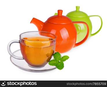 Glass cup of tea with mint leaves and two teapots isolated on white background