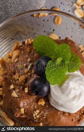 Glass cups of chocolate and chestnuts mousse with roasted almonds and oats decorated with black berries and mint leaves.