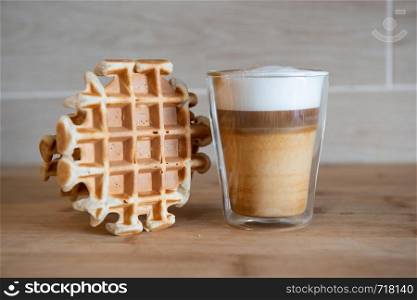 Glass cups of multilayer coffee with mini stroopwafel, syrupwaffles cookies on light gray background with copy space. waffle cookies. Glass cup of multilayer coffee with mini stroopwafel, syrupwaffles