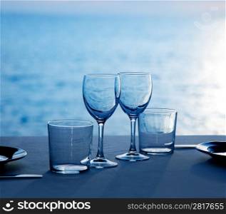 Glass dish cups and glasses on blue sea background