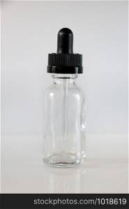 Glass dropper bottle and pipette on grey background. Glass dropper bottle on grey background