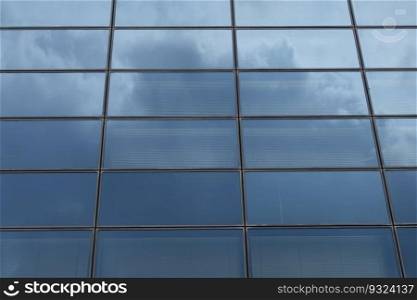 Glass facade of modern building with sky reflections abstract background.