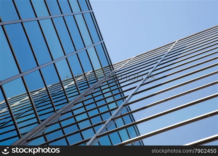glass facade of modern office building and reflections of blue sky