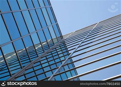 glass facade of modern office building and reflections of blue sky
