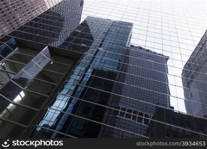glass facade of skyscraper in new york downtown manhattan with reflections of other skyscrapers and sky
