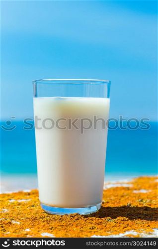 Glass filled with cow milk blue sea and sky