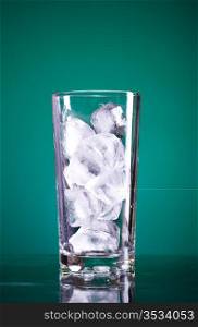 glass full of ice on green background