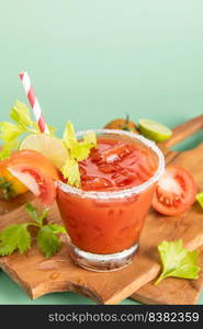 glass glass of tomato juice, lime with fresh bright bunch of tomatoes isolated on green background, green parsley. vegetable drink.