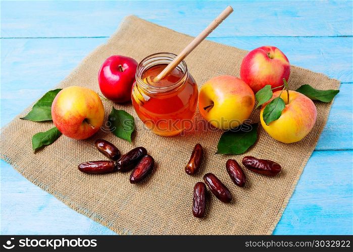 Glass honey jar, dates and apples on burlap napkin. Jewesh new year symbols. Rosh hashanah concept. Organic fruits.. Glass honey jar, dates and apples on burlap napkin