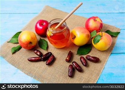 Glass honey jar, dates and apples on burlap napkin. Jewesh new year symbols. Rosh hashanah concept. Organic fruits.. Glass honey jar, dates and apples on burlap napkin