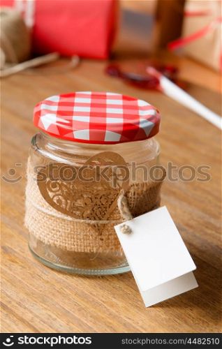Glass jar decorated for Valentine's Day gift on wooden background