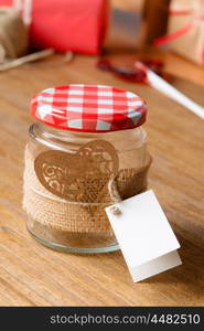 Glass jar decorated for Valentine's Day gift on wooden background