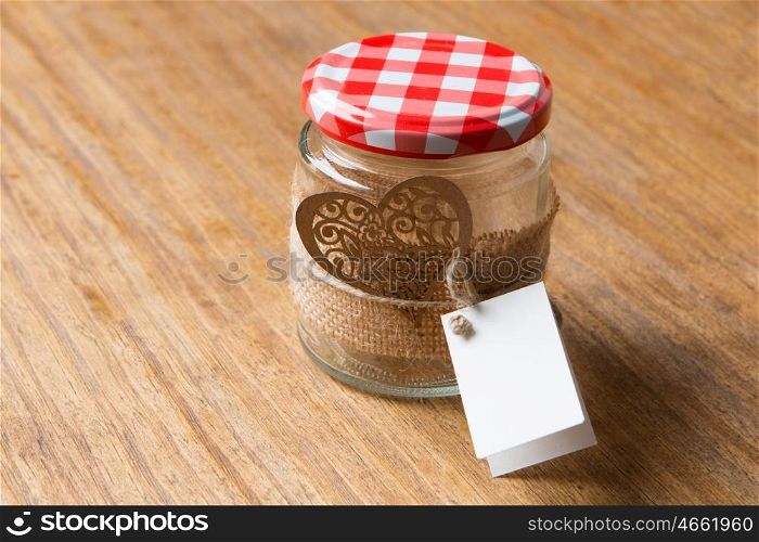 Glass jar decorated for Valentine's Day gift on wooden background