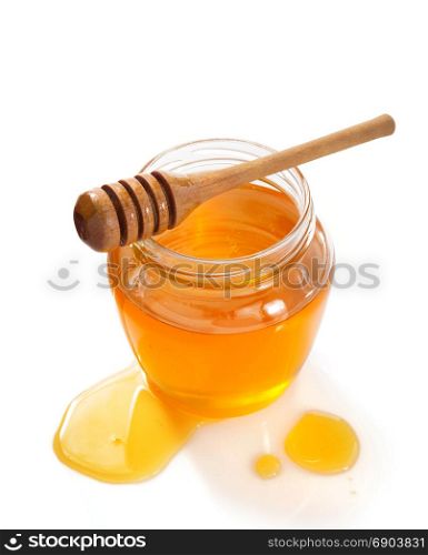 glass jar full of honey and dipper isolated on white background