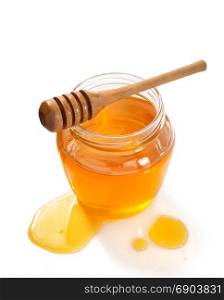 glass jar full of honey and dipper isolated on white background