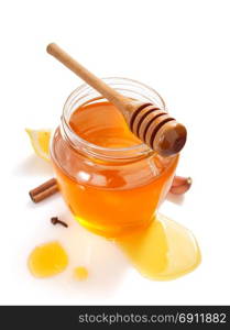 glass jar full of honey and dipper isolated on white background