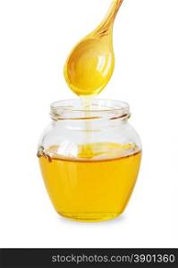 Glass jar of golden honey with immersed in it a wooden spoon