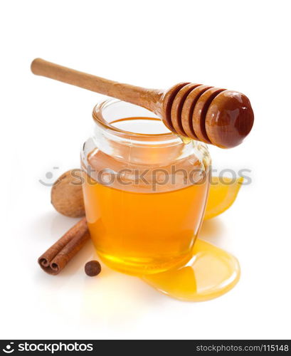 glass jar of honey and dipper isolated on white background