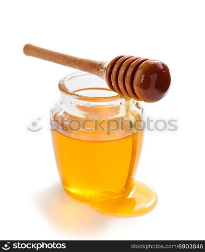 glass jar of honey and dipper isolated on white background