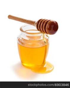 glass jar of honey and dipper isolated on white background