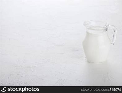 Glass jar of milk on white stone kitchen table background.