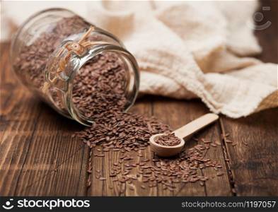 Glass jar of raw natural organic linseed flax-seed with spoon and linen cloth on wood background.