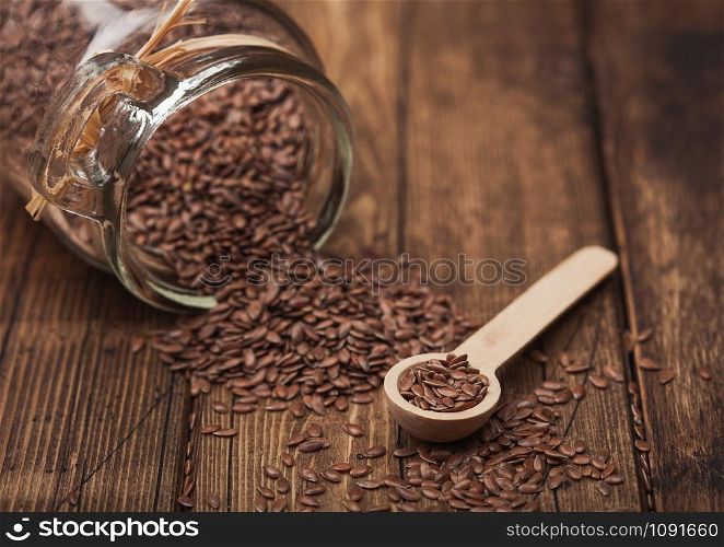 Glass jar of raw natural organic linseed flax-seed with spoon on wood background. Healthy omega 3 product.