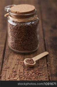 Glass jar of raw natural organic linseed flax-seed with spoon on wood background. Healthy omega 3 product.