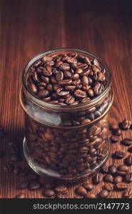 Glass jar with beans on wooden background. Glass jar with coffee beans