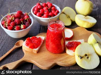 Glass jar with different kinds of berry and fruit on wooden table. Apple, raspberry, hawthorn jam .. Glass jar with different kinds of berry and fruit on wooden table. Apple, raspberry, hawthorn jam