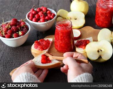 Glass jar with different kinds of berry and fruit on wooden table. Apple, raspberry, hawthorn jam .. Glass jar with different kinds of berry and fruit on wooden table. Apple, raspberry, hawthorn jam