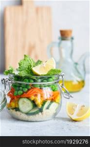 Glass jar with fresh raw vegetables and couscous groats. Healthy Meal Prep - recipe preparation photos. Healthy vegan dishes in glass containers. Weight loss food concept. Homemade Salad in a jar.