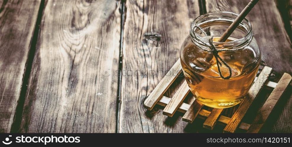 Glass jar with natural honey and a spoon. On wooden background.. Glass jar with natural honey and a spoon.