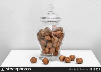 Glass jar with walnuts on table on a white background. Glass jar with walnuts on table on a white background. Healthy tasty organic food concept