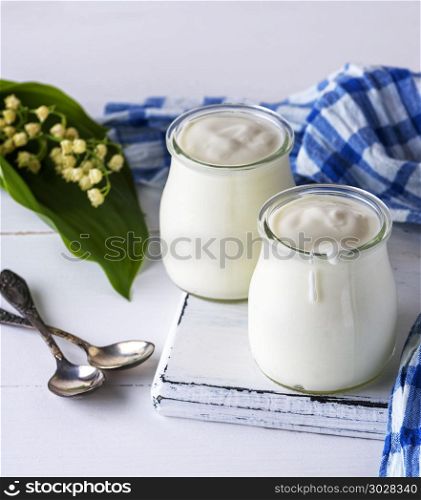 glass jars with homemade yogurt on a white wooden board, close up. glass jars with homemade yogurt