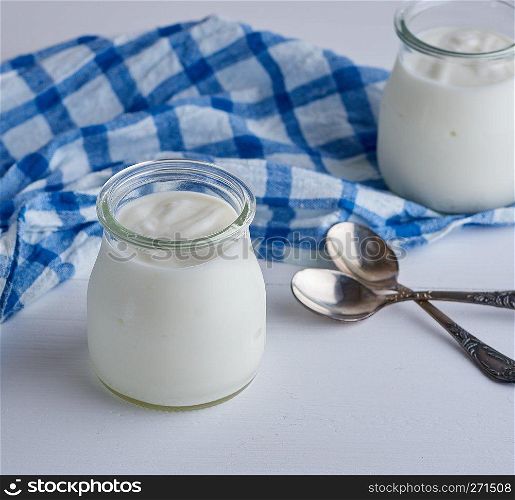 glass jars with homemade yogurt on a white wooden board,  top view