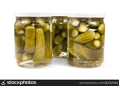 glass jars with preserved cucumbers on a white background.