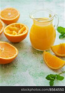 Glass jug of fresh orange juice with fresh fruits
