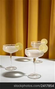 glass margarita cocktail garnish with lime table against yellow curtain