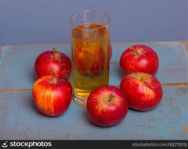 Glass of apple juice and a red apples on a blue old wooden background