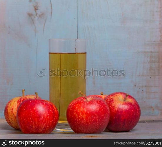 Glass of apple juice and a red apples on a blue old wooden background