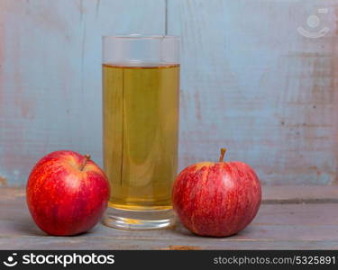 Glass of apple juice and a red apples on a blue old wooden background