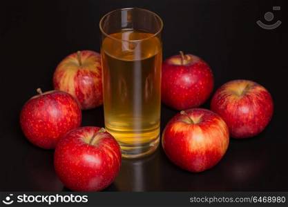 Glass of apple juice and a red apples on a dark wooden background