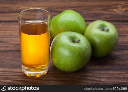 Glass of apple juice and apples on wood. Glass of apple juice and apples on wooden background